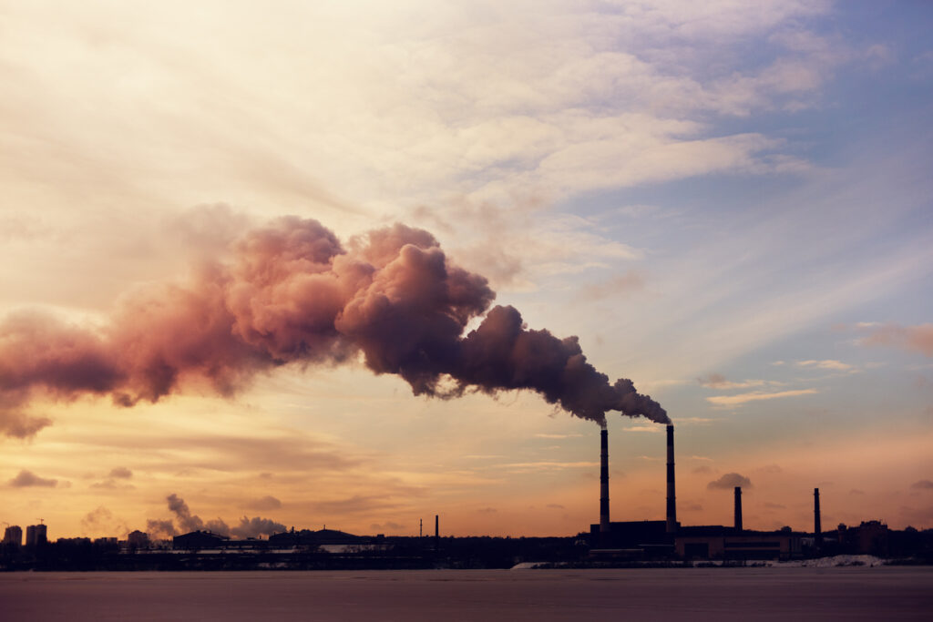 Various smokestacks emitting smoke amidst a sunset backdrop, reflecting emissions to be reduced through supply chain decarbonization initiatives like zeigo | sustainability software solution